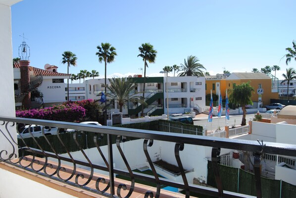 A residential area with a building labeled "ASCONA," featuring balconies with metal railings, palm trees, and a clear blue sky. - Atlantic Sun Beach - Gay Men Only (San Bartolomé de Tirajana)