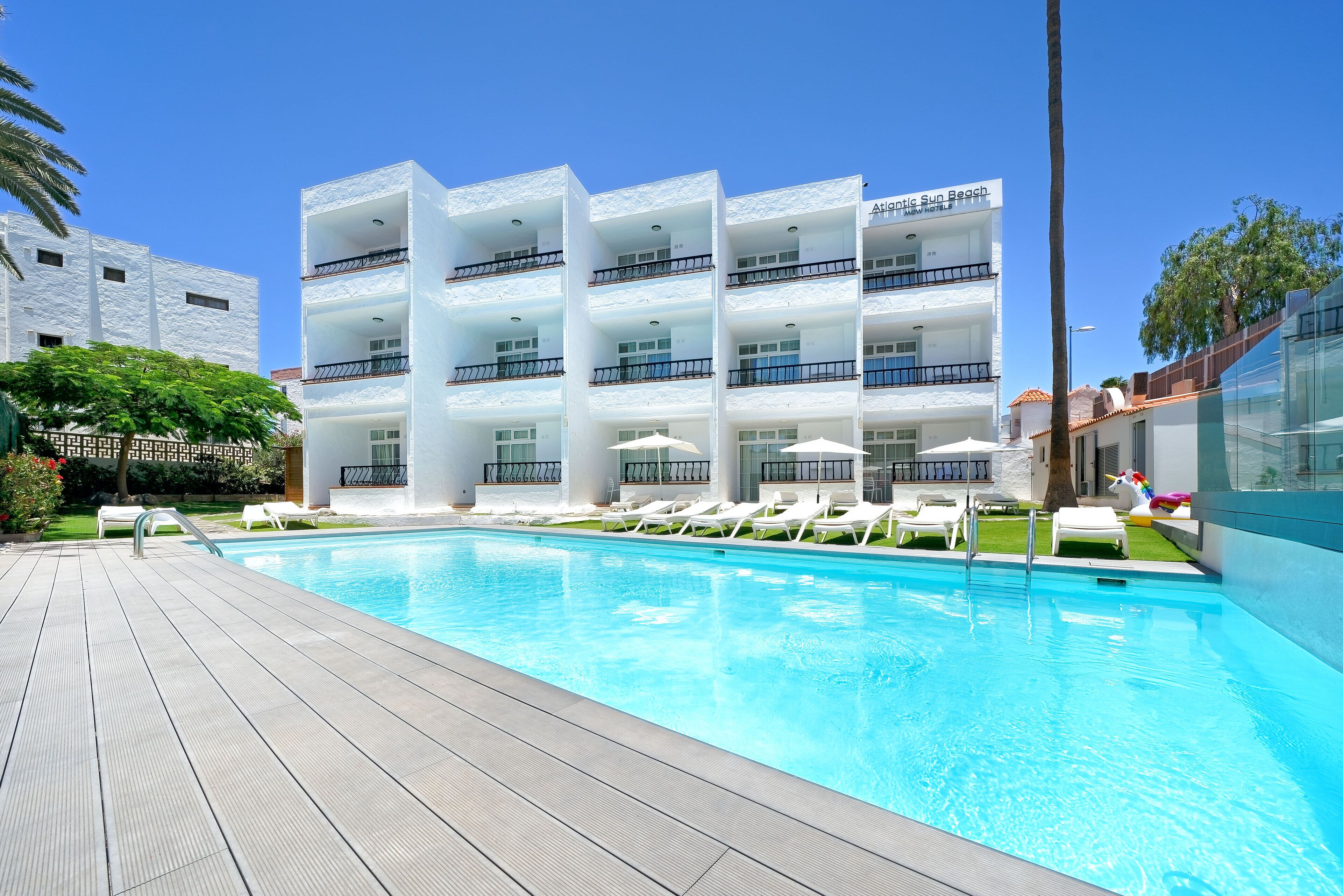 Une piscine avec des chaises longues et un bâtiment doté de balcons.