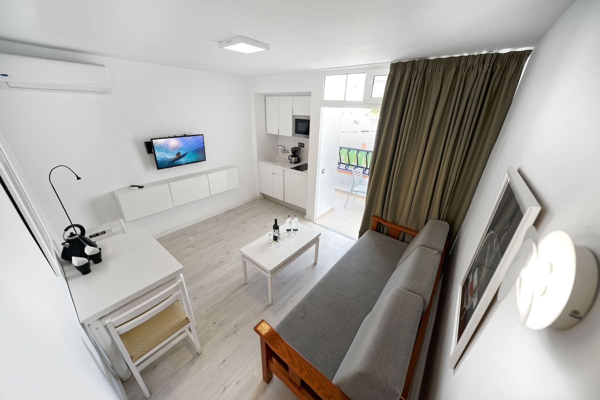 Ein modernes Wohnzimmer mit Sofa, Couchtisch, Fernseher und Küchenzeile.