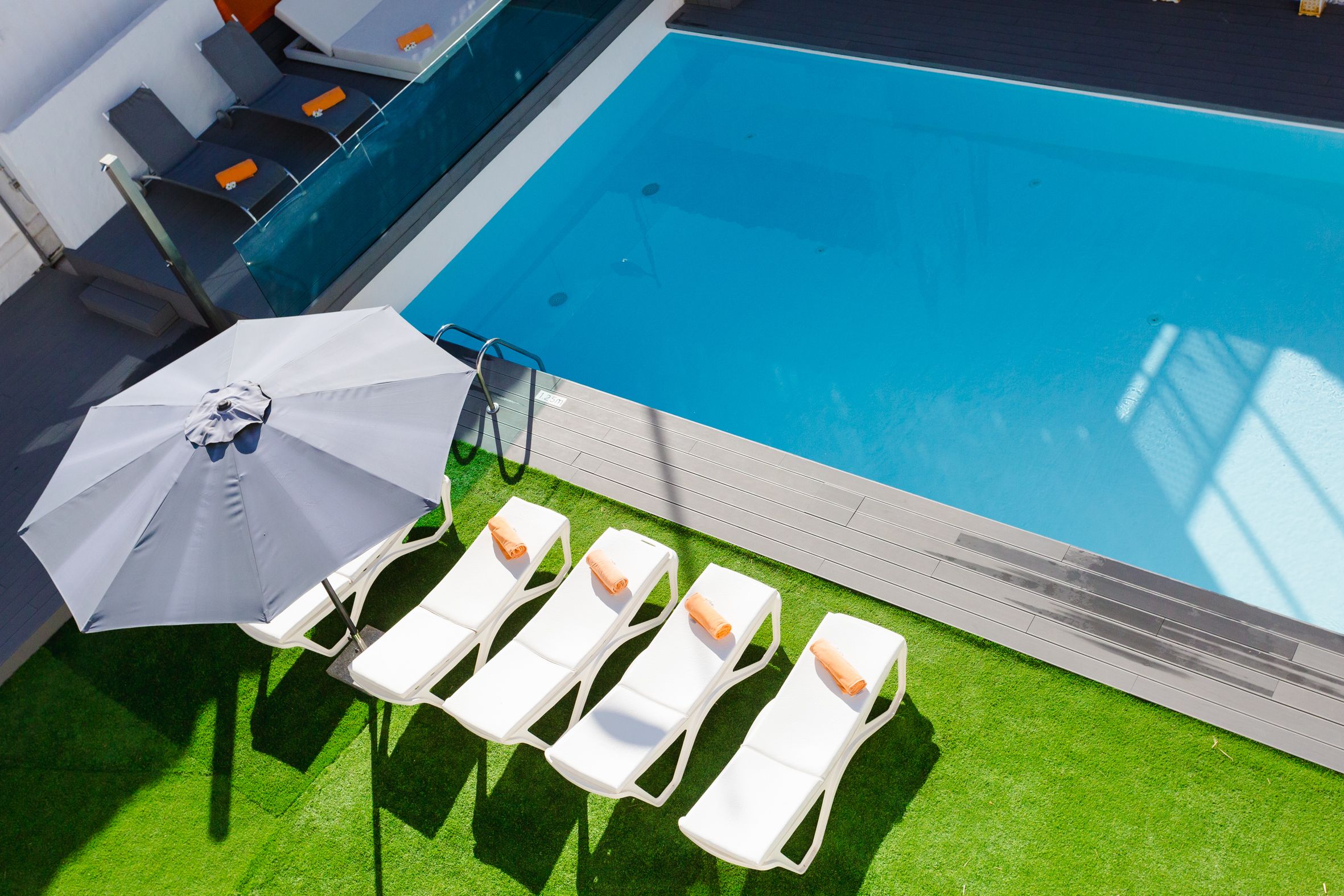 Une piscine avec des chaises longues blanches et un parasol blanc.