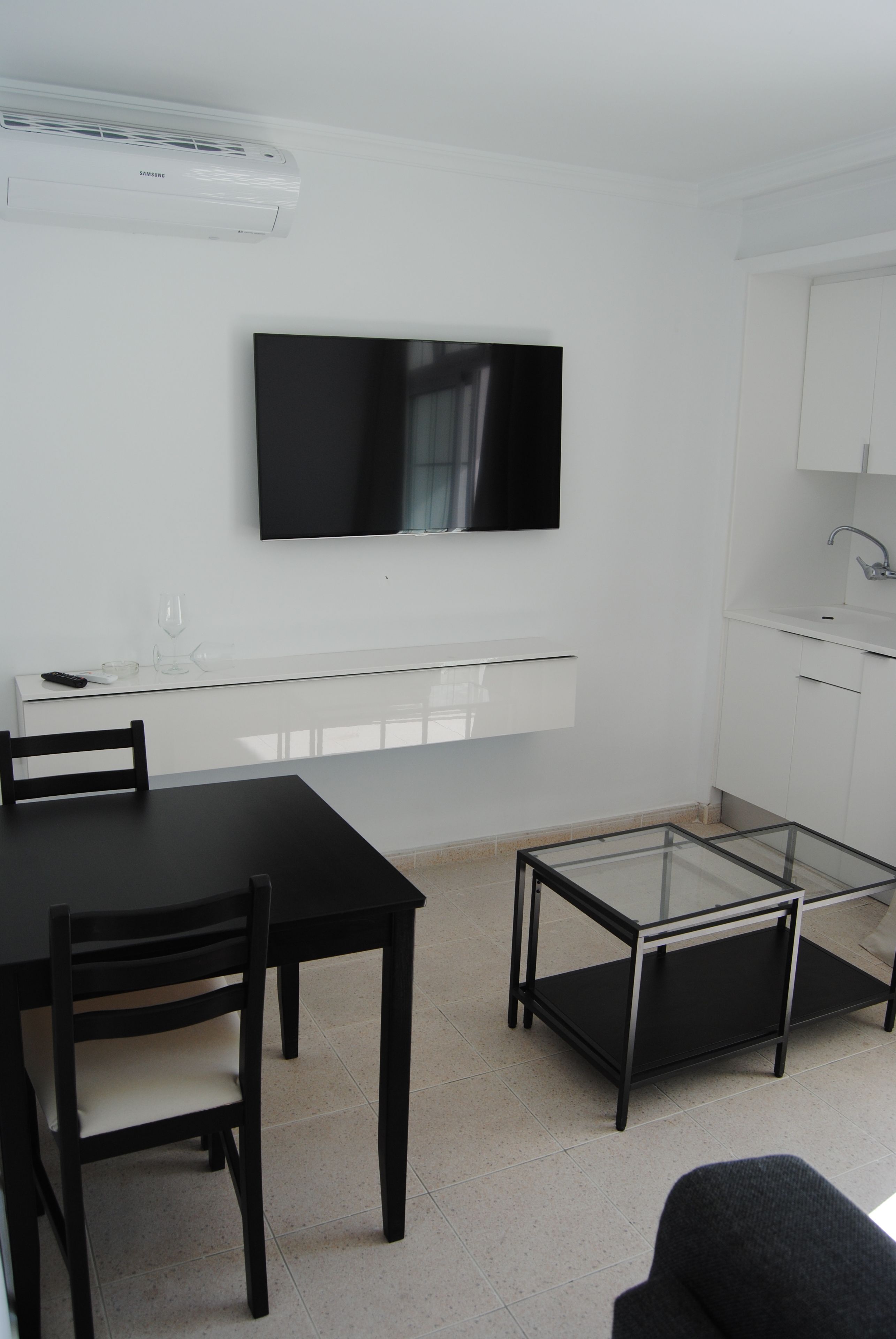 Una cocina moderna con armarios blancos, lavavajillas incorporado y televisor de pantalla plana montado en la pared.