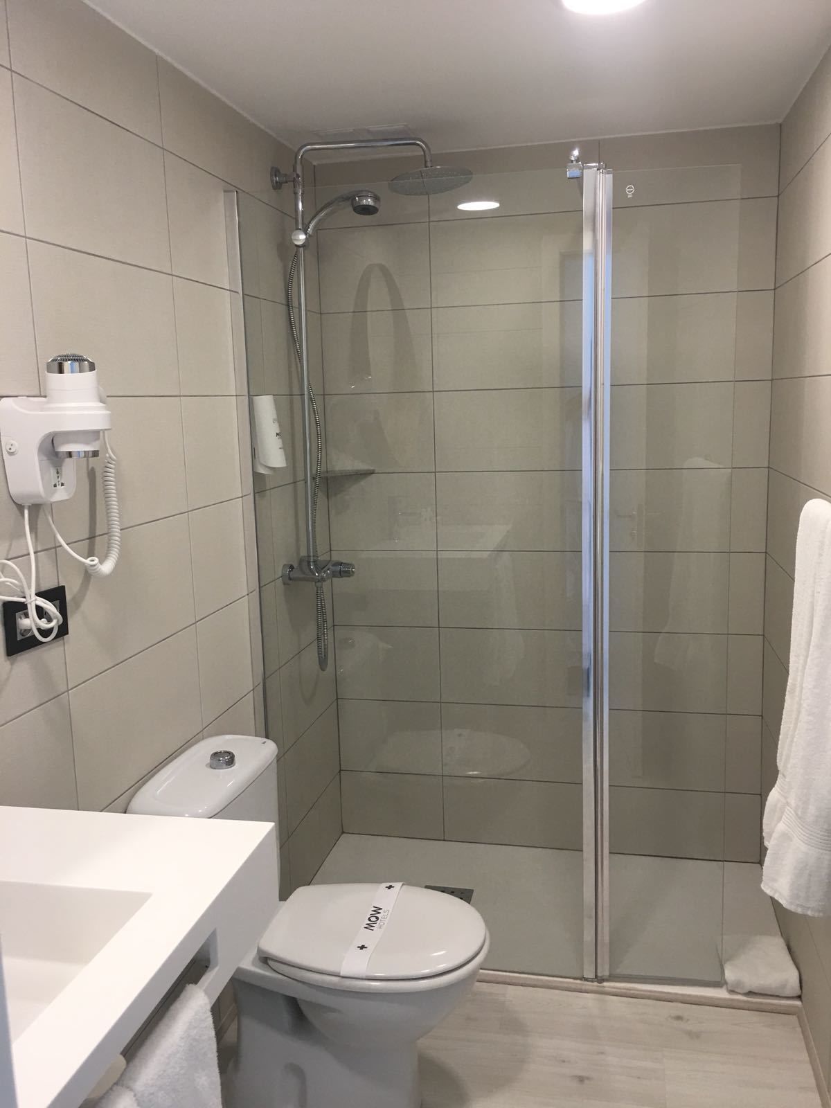 A modern bathroom with a glass-enclosed shower, a toilet, and a sink.