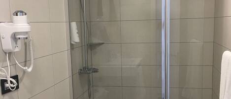 A modern bathroom with a glass-enclosed shower, a toilet, and a sink.