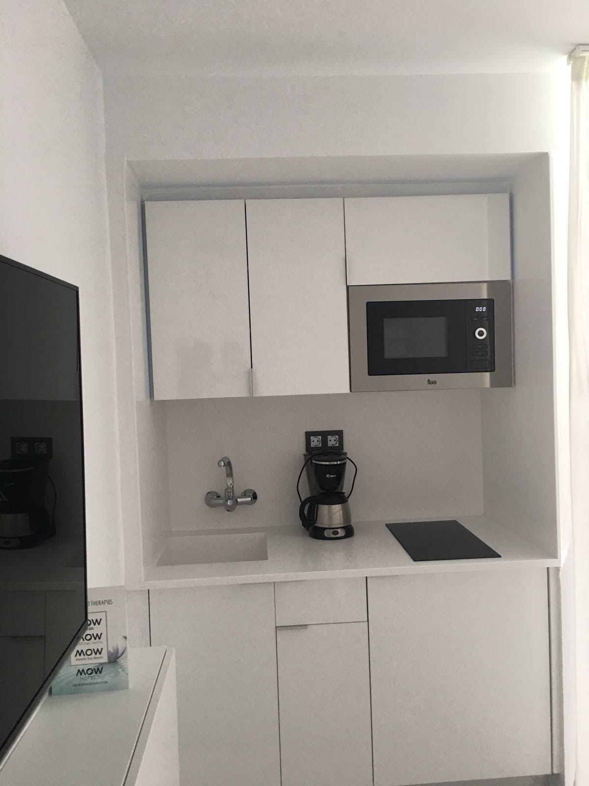 A compact kitchenette with a microwave, coffee maker, and a small sink.
