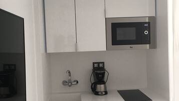 A compact kitchenette with a microwave, coffee maker, and a small sink.