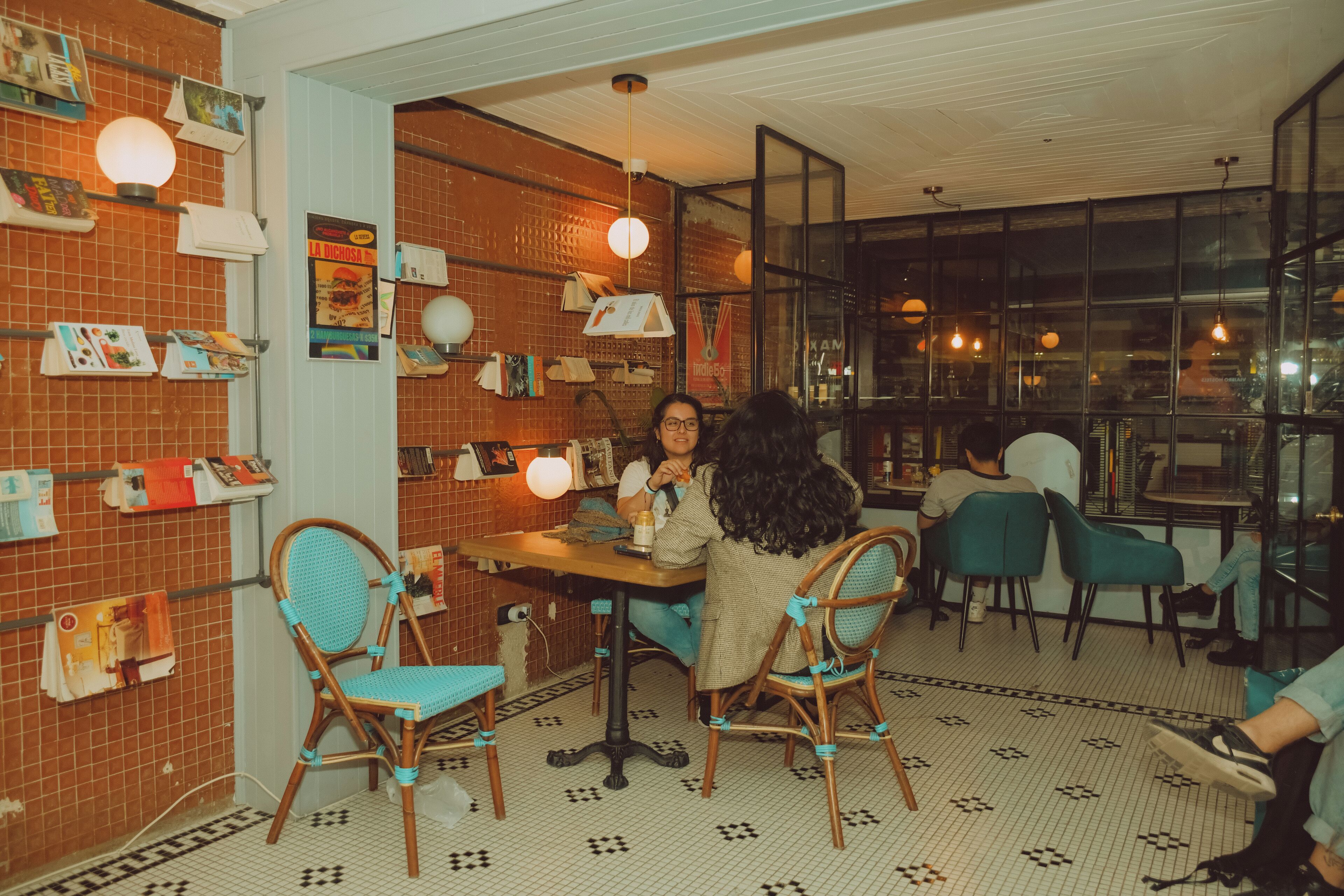 A cozy cafe with brick walls, wooden chairs, and a tiled floor.