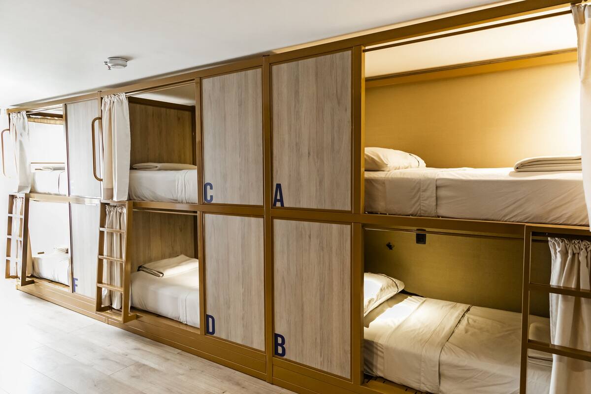 A bunk bed room with wooden frames and white bedding.