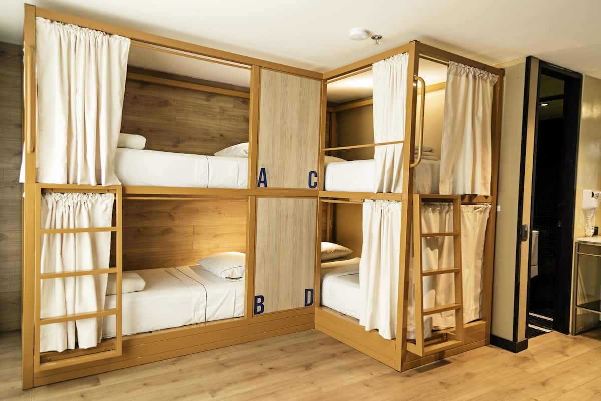 A bunk bed room with wooden frames and white bedding.