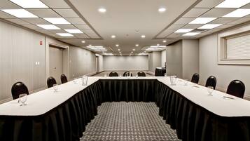 A conference room with a long table, chairs, and a patterned carpet.