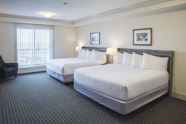 A hotel room with two beds, a chair, and a large window.