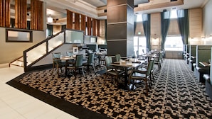 Un moderno vestíbulo de hotel con una escalera, zona de comedor y alfombra estampada.