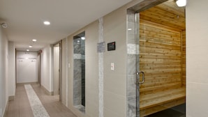 Un pasillo con un letrero de vestuario, una sauna de madera y suelo de baldosas.