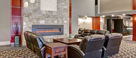 A lobby with leather seating, a fireplace, and a patterned carpet.