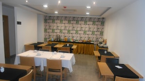 A conference room with tables and chairs, a long table with a yellow tablecloth, and a wall with a patterned design. - Hotel Ritz Capital (Luanda)