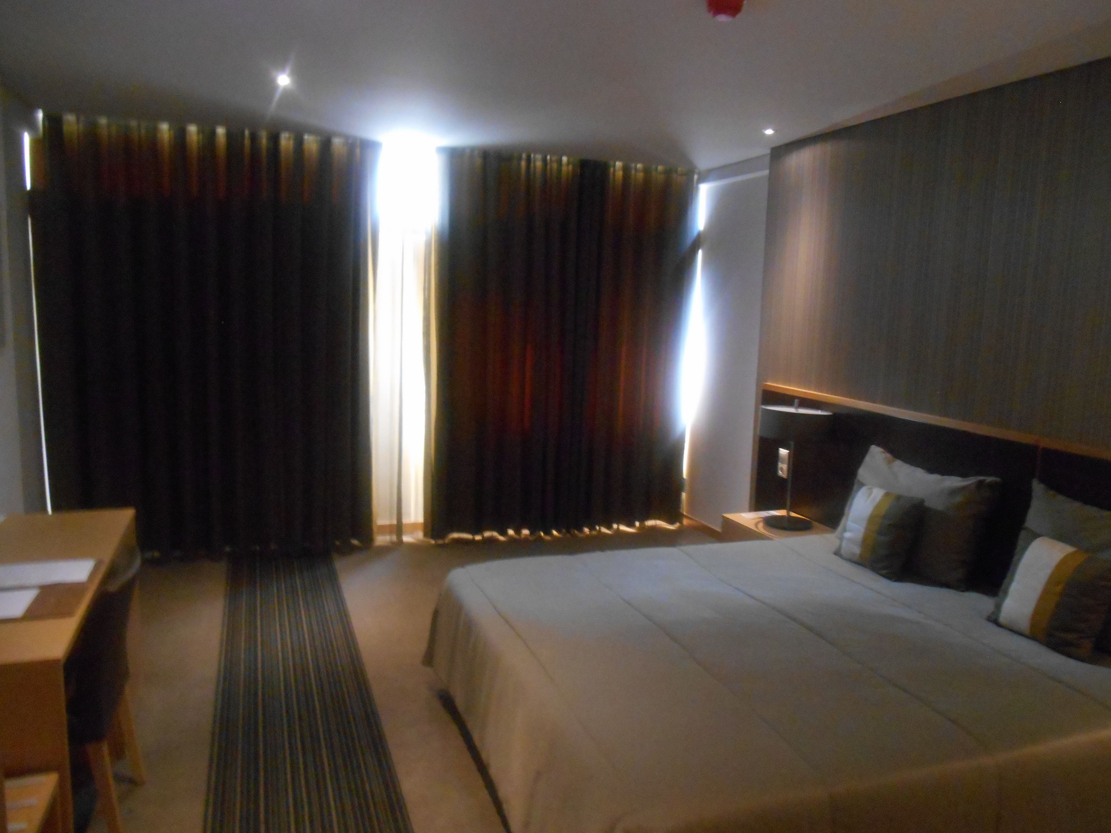Una habitación de hotel con cama, escritorio y cortinas.