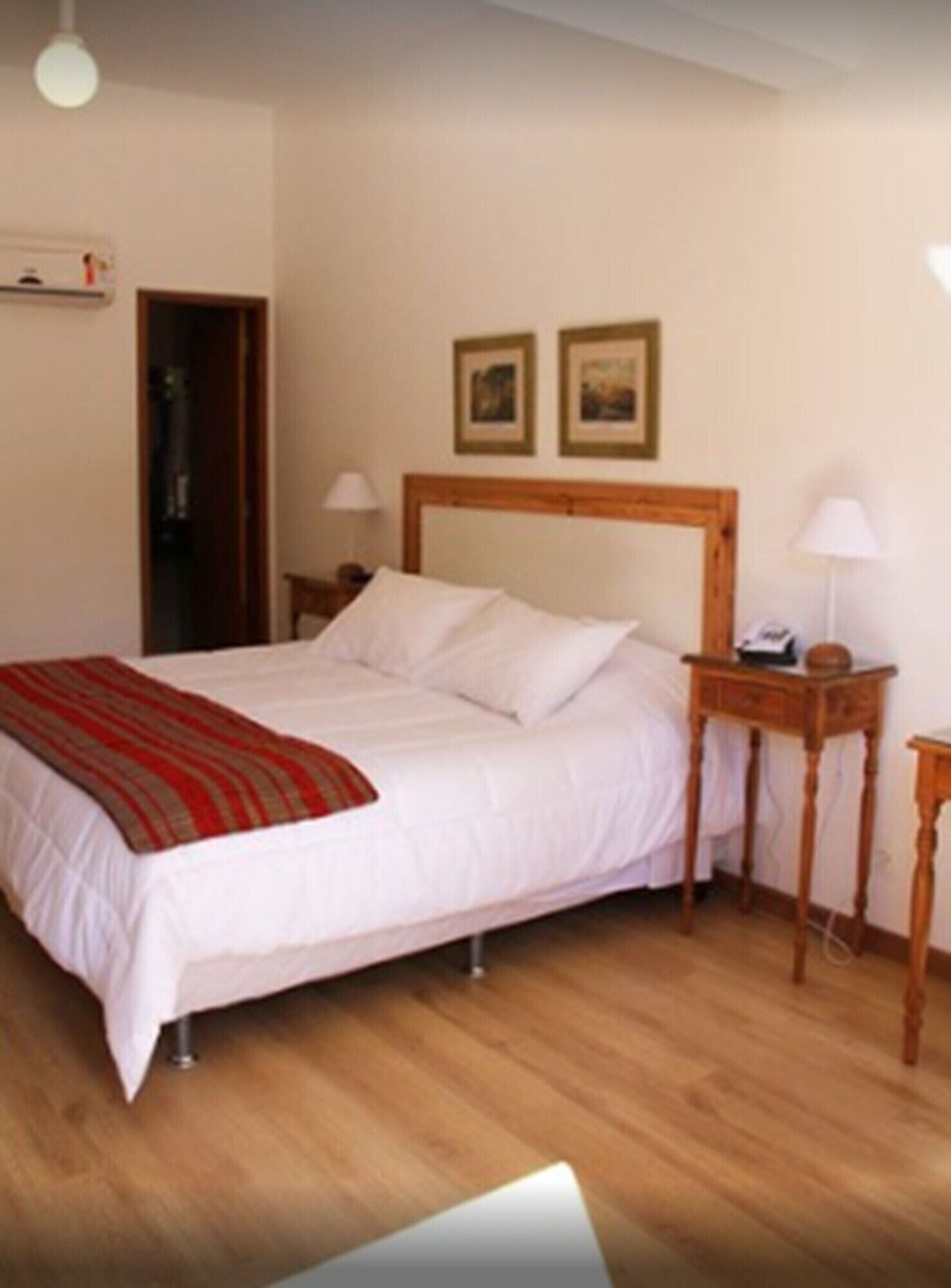 A neatly made bed with a red and white striped blanket, a wooden headboard, and two bedside tables with lamps.