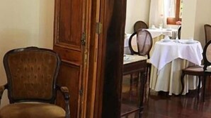 A dining area with wooden chairs, a table set for two, and a wooden door. - Casablanca Koeler Hotel (Petrópolis)