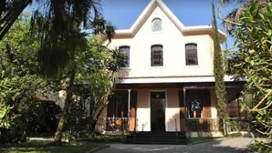 A two-story building with a symmetrical facade, a central entrance with steps, and a small triangular pediment above the door. - Casablanca Koeler Hotel (Petrópolis)
