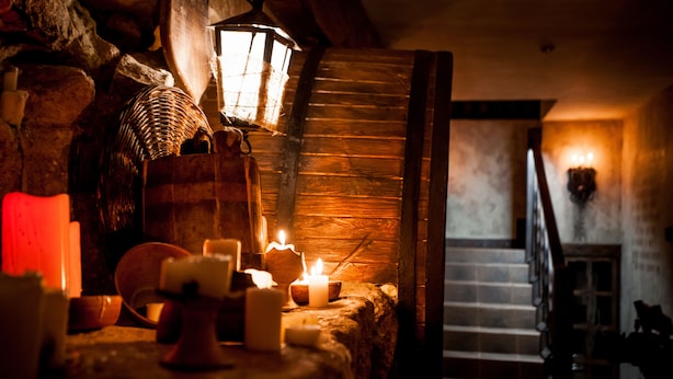 Una habitación acogedora con una escalera de madera, una pared de piedra y una mesa con velas.