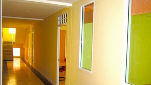 A hallway with yellow walls, a black and yellow patterned floor, and a large window with a green view. - Dariva Place (Pattaya)