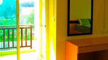A room with a sliding glass door leading to a balcony, an air conditioning unit mounted on the wall, and a framed picture above a vanity.