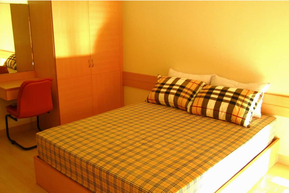 Une chambre à coucher avec un lit, une chaise rouge, un miroir et une table de chevet.
