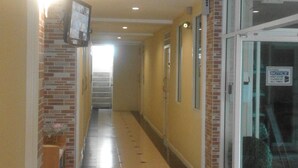 A corridor with tiled flooring, a brick wall on one side, and a glass door on the other. - Dariva Place (Pattaya)