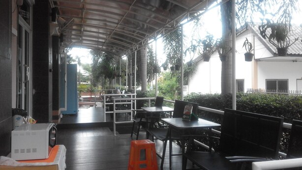 A covered outdoor seating area with tables and chairs, a coffee machine, and potted plants. - Dariva Place (Pattaya)