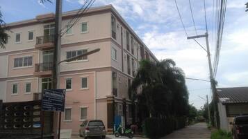 A multi-story residential building with balconies, a parked car, and a scooter.