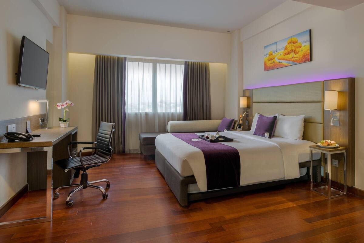 Una habitación de hotel con cama, escritorio, silla y televisor.