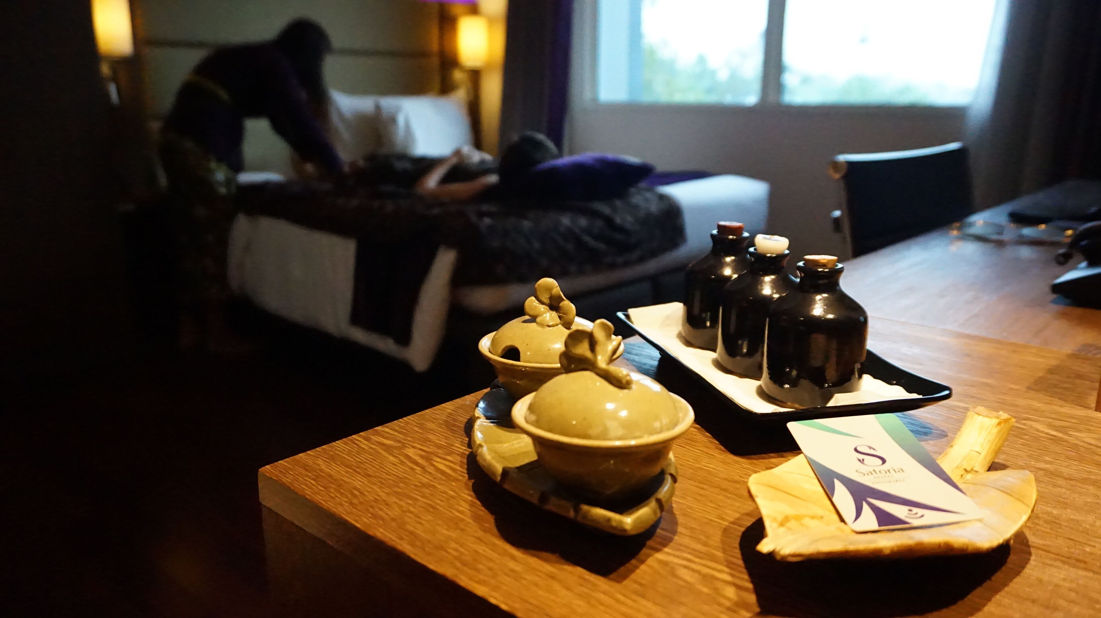 A wooden table with a teapot, teacups, and a tray of condiments.