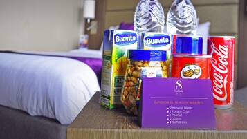 A hotel room with a bed, a wooden nightstand, and a sign listing room benefits.