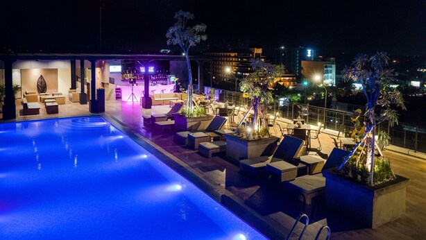 Un área de piscina en la azotea con sillones reclinables y un bar.