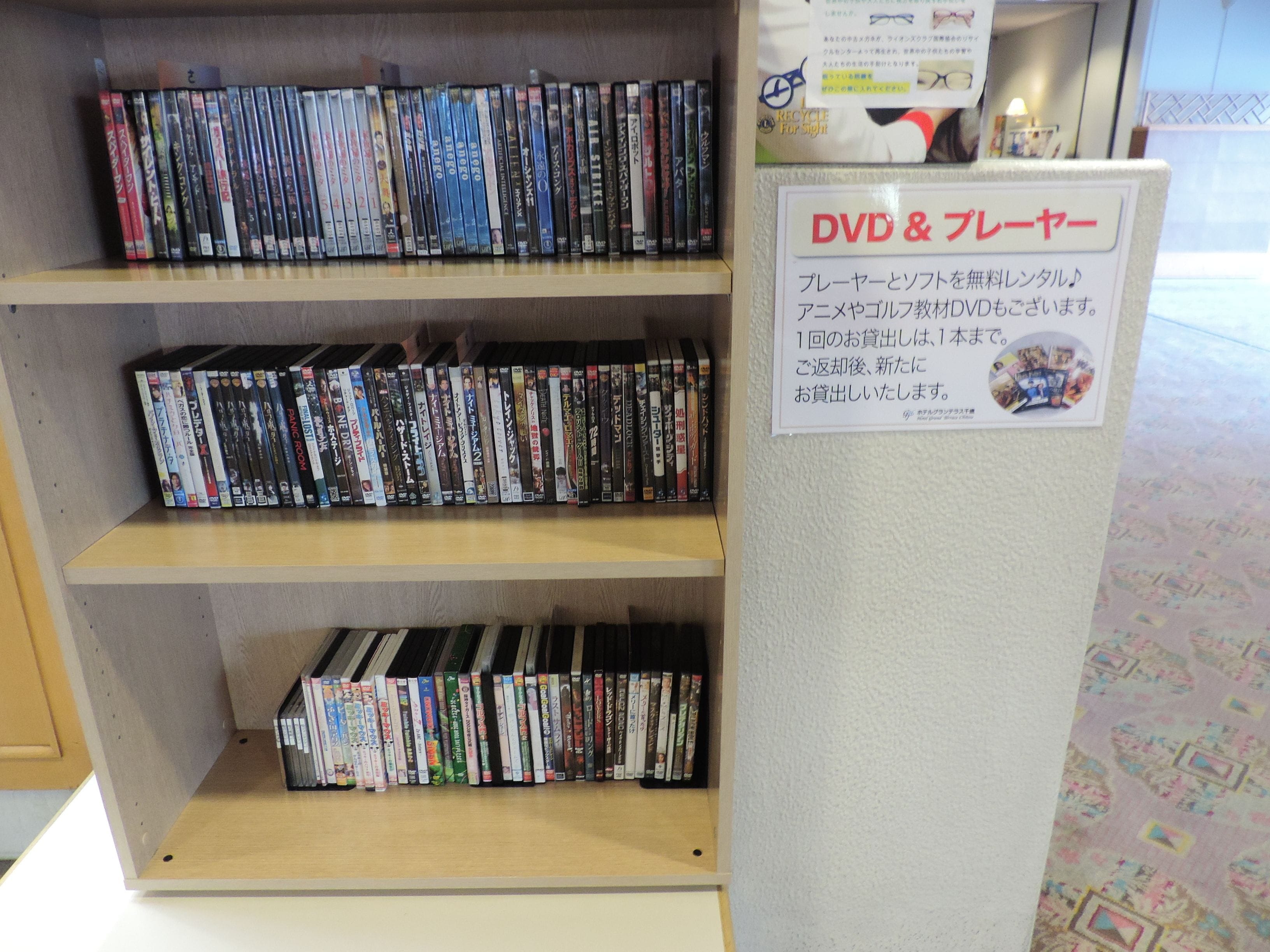 Una sección de alquiler de DVD y videos con varias estanterías llenas de discos y un cartel con las políticas de alquiler.