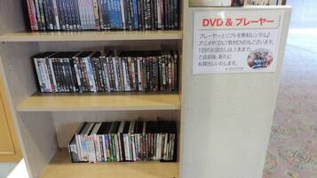 Una sección de alquiler de DVD y videos con varias estanterías llenas de discos y un cartel con las políticas de alquiler.