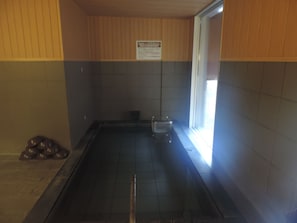 Un sauna avec un sol carrelé, un banc et une fenêtre.