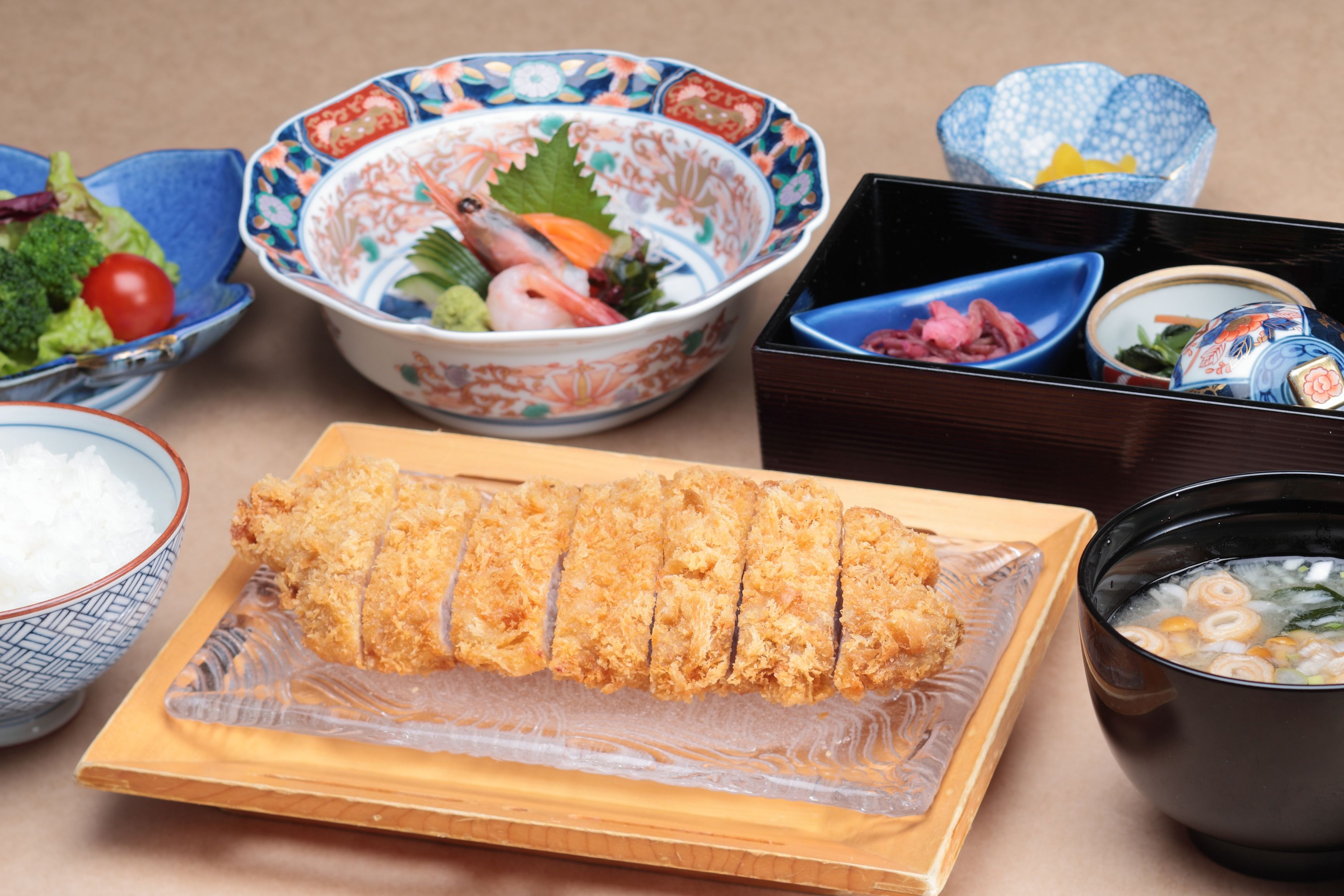 Diversos pratos, incluindo sushi, sashimi e uma tigela de sopa, dispostos sobre uma mesa.