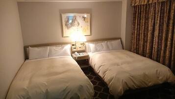 A hotel room with two single beds, a nightstand with a lamp, and a painting on the wall.