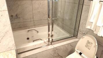 A bathroom with a glass-enclosed shower, a bathtub, and a toilet.