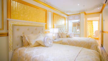 A luxurious hotel room with two large beds, ornate headboards, and a mirror reflecting the room.