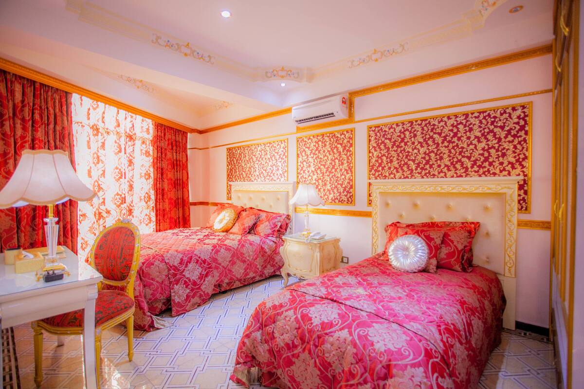 A hotel room with two beds, a desk, a chair, and a nightstand.