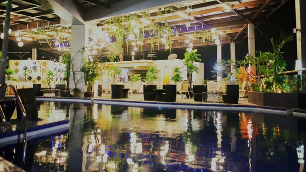 An indoor swimming pool with a tiled edge, surrounded by potted plants and tables. - Lace Boutique Hotel (Johor Bahru)