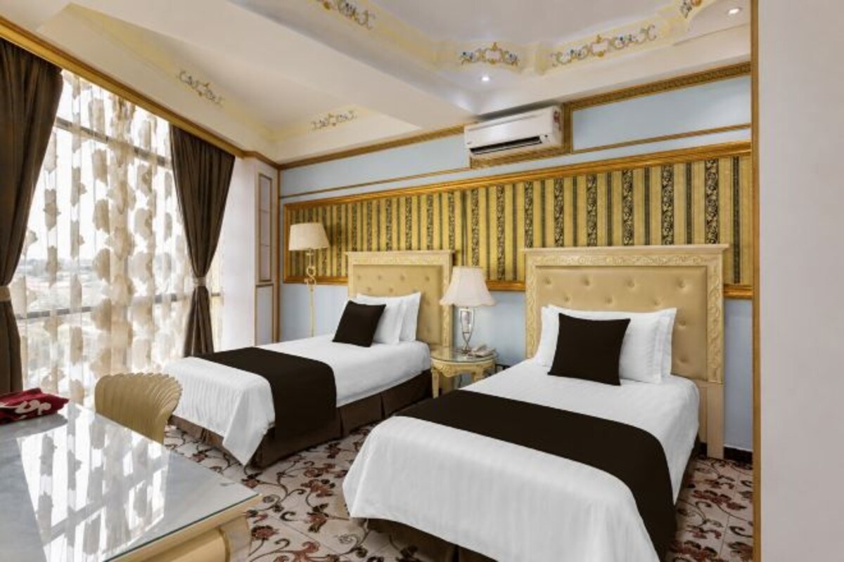 Ein Hotelzimmer mit zwei Betten, einem Schreibtisch und einem Sessel.
