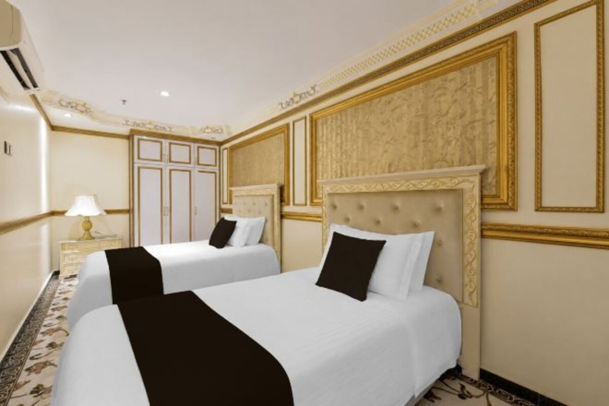A hotel room with two beds, a chandelier, and a decorative wall panel.