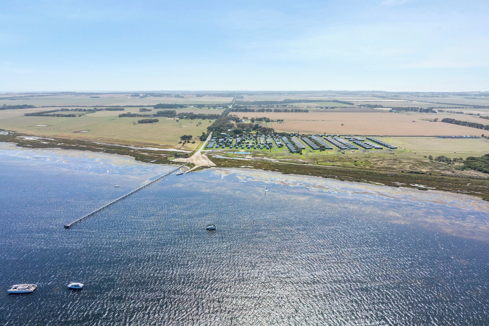 An aerial view of a coastal area with a bridge connecting to a marina.