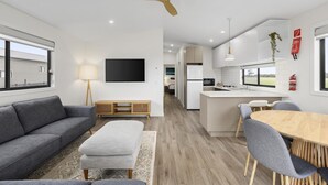 A modern living room with a grey sofa, a wooden coffee table, and a ceiling fan. - Swan Bay Holiday Park (Swan Bay)