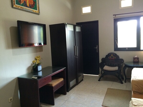 A hotel room with a TV, a wardrobe, a desk with a chair, a small table with a tissue box, and a window with a view.