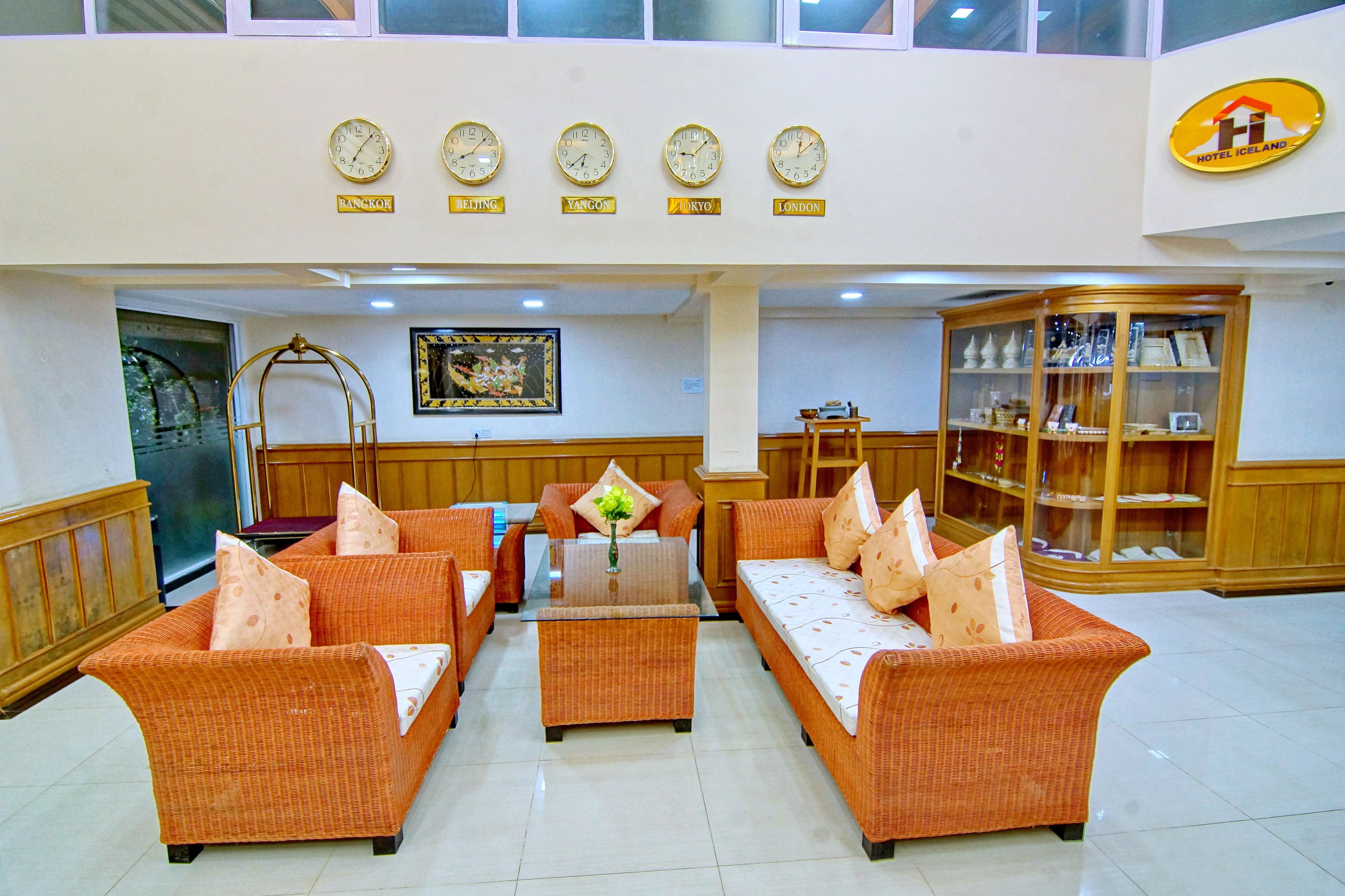 A lobby with wicker furniture, clocks indicating different cities, and a display cabinet.