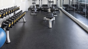 A gym with exercise equipment, a wall of dumbbells, and a large window. - Clover Suites Royal Lake Yangon (Yangon)