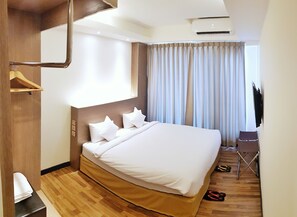 A hotel room with a large bed, a wooden wardrobe, a desk, and a TV. - Clover Suites Royal Lake Yangon (Yangon)